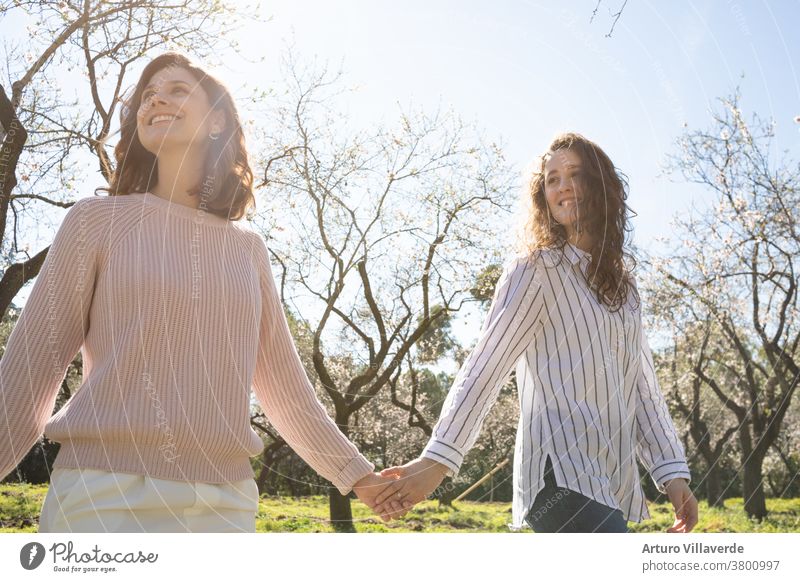 a couple of girls walking hand in hand in a park on a sunny day. They walk around smiling and happy activity background pretty Bright negligent Cheerful