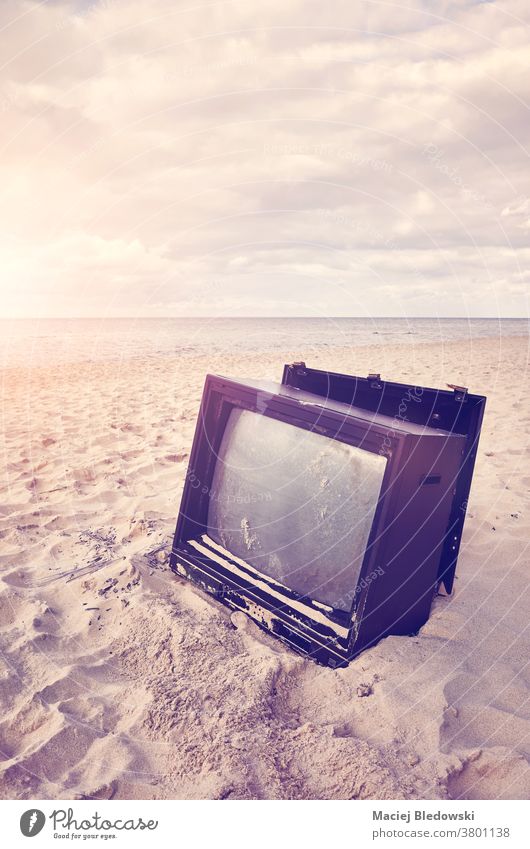 Old broken TV set on a beach at sunset. television sand screen obsolete news nature old technology instagram effect filtered vintage sky peaceful relax media