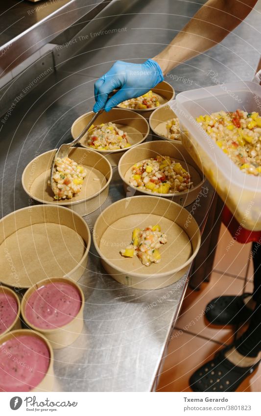 Cook preparing rice salads to take away. The containers used are compostable. takeaway food ice cream cook kitchen hand utensil glove hygienic glove restaurant