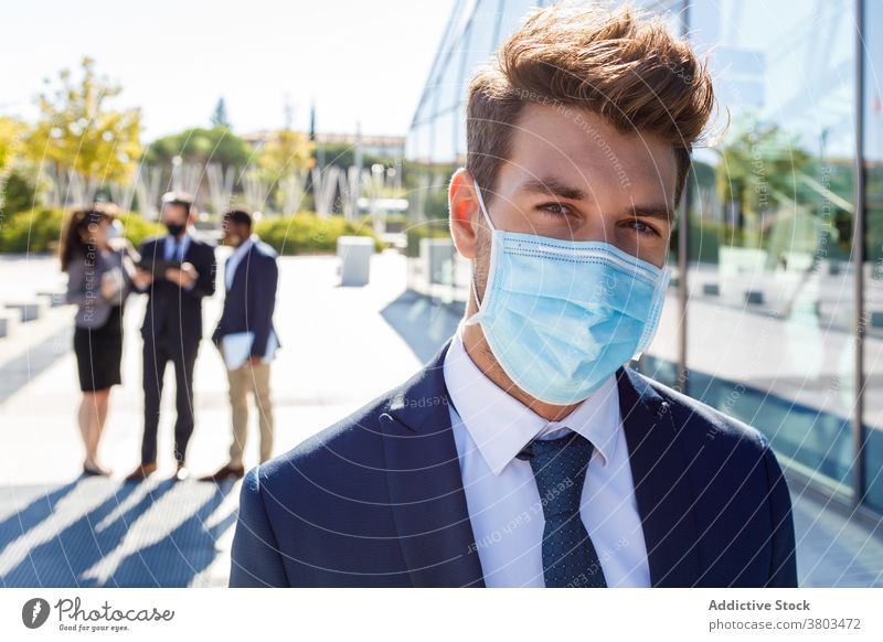 Thoughtful young male entrepreneur standing on street in sunlight man serious thoughtful businessman formal work new normal colleague discuss communicate