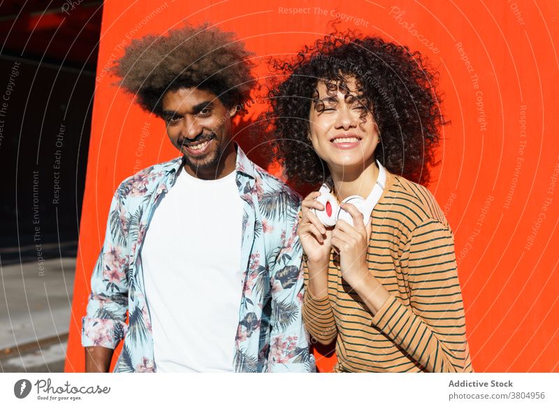 Happy couple standing near red wall stylish afro hairstyle cool together street bright trendy wear masculine macho beard smile ornament happy sincere