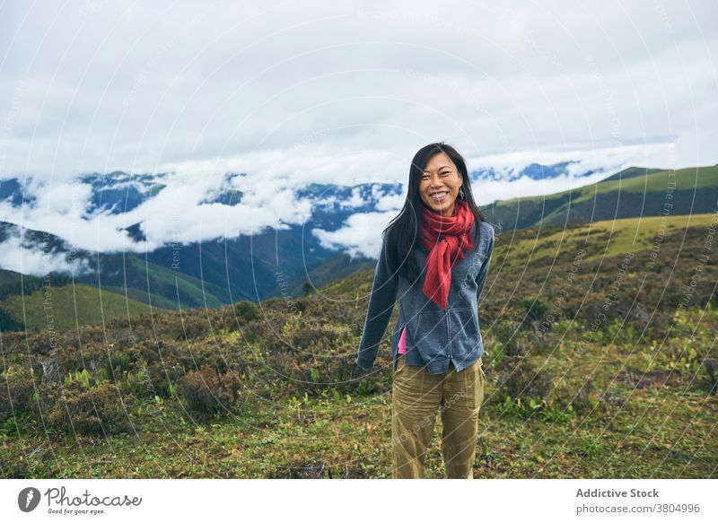 Happy ethnic female hiker in mountain valley woman travel hill meadow highland wanderlust slender cheerful toothy smile slim skinny nature environment landscape