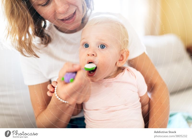 Cheerful mother feeding adorable baby woman infant eat childcare bonding childhood female kid cute toddler room parent love together motherhood lady innocent