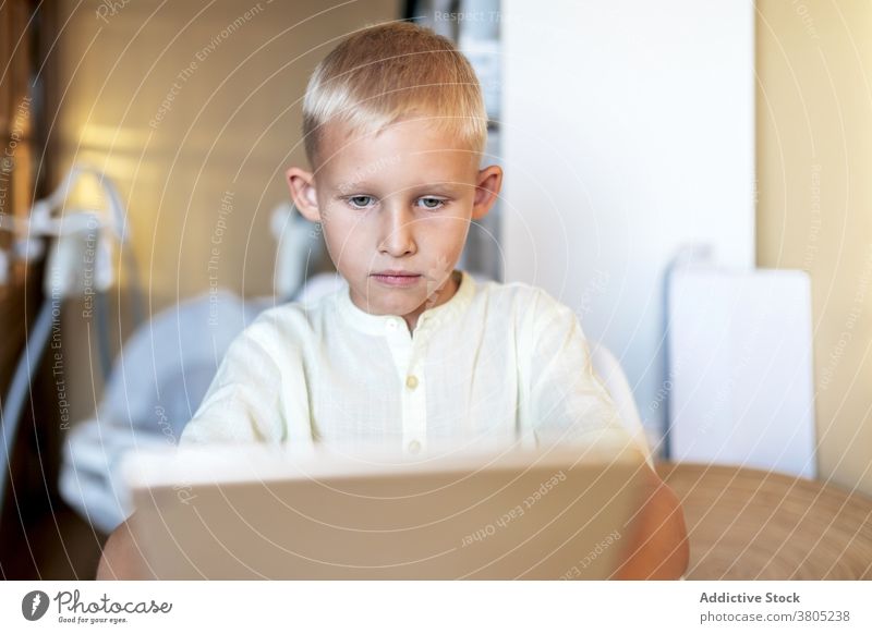 Focused boy watching films on tablet browsing kid child smart leisure serious concentrate online blond internet gadget device surfing connection modern focus
