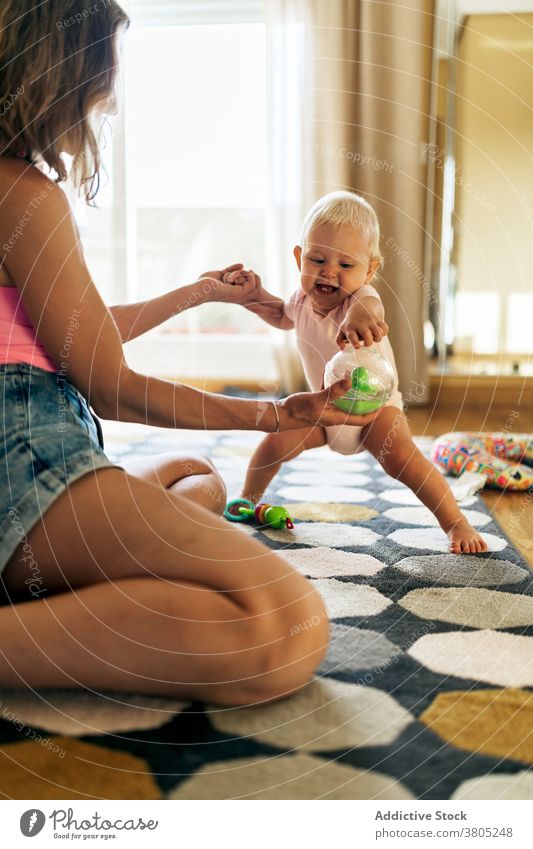 Cheerful mother and baby girl playing on floor woman home happy having fun toy grimace love daughter together adorable young child toddler motherhood cute joy