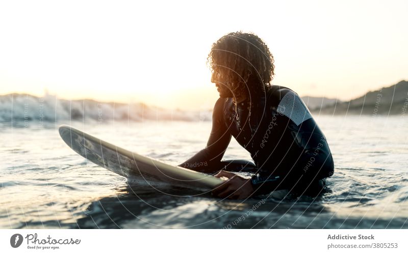 Concentrated surfer looking at coming wave man sea ocean water sports summer focus leisure surfboard male serious pensive curly hair wetsuit vacation beach