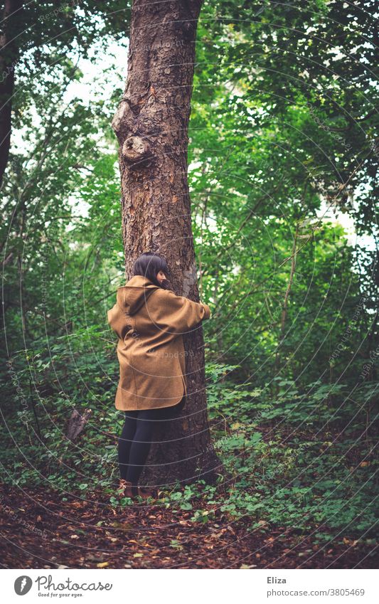A young woman is standing in the forest and hugs a tree. Nature conservation and environmental protection. Forest nature conservation Environmental protection