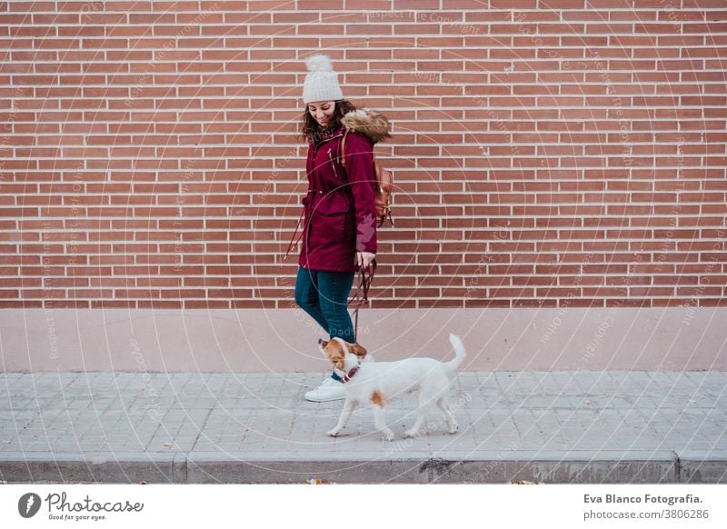 woman at the city walking with her adorable jack russell dog. Lifestyle outdoors autumn brick wall bulldog casual clothing caucasian cheerful coat cold collar