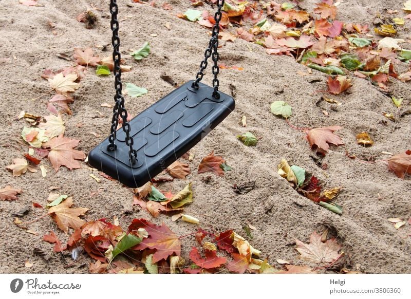 Autumn atmosphere on the playground - swing hangs over rain-soaked sandy ground covered with autumn leaves Swing Playground Shadow Maple leaf Autumnal colours