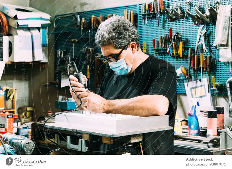 Professional workman in mask soldering details in workshop craftsman focus workplace profession small business handyman instrument concentrate professional