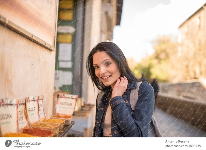 Pretty woman smelling, spices; Spanish text: "curcuma, cous cous, spice, paprika" She is doing tourism in Granada, Spain Visiting sites near to “La Alhambra”.