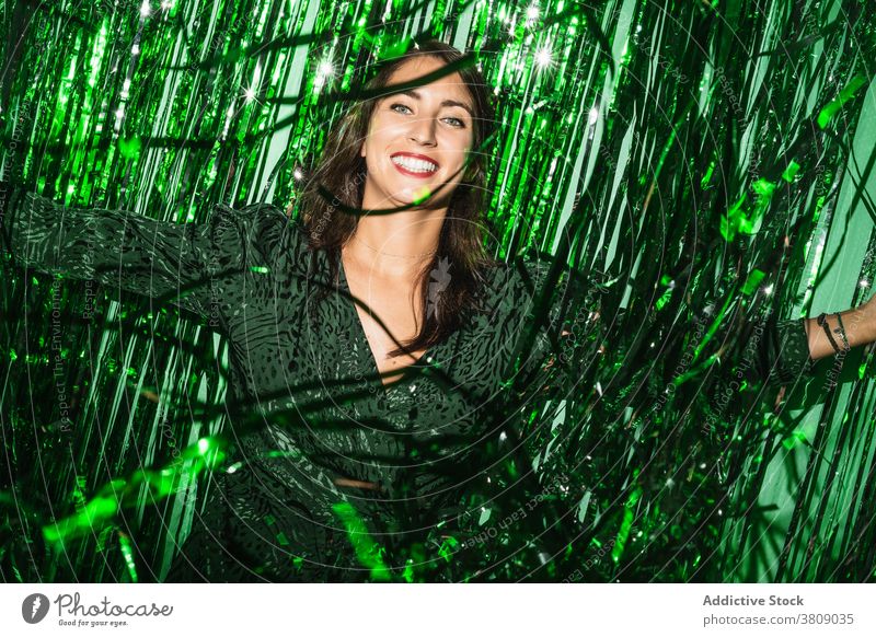 Cheerful woman playing with green tinsel party stripe having fun playful foil color vibrant female shiny dress festive happy cheerful delight enjoy trendy