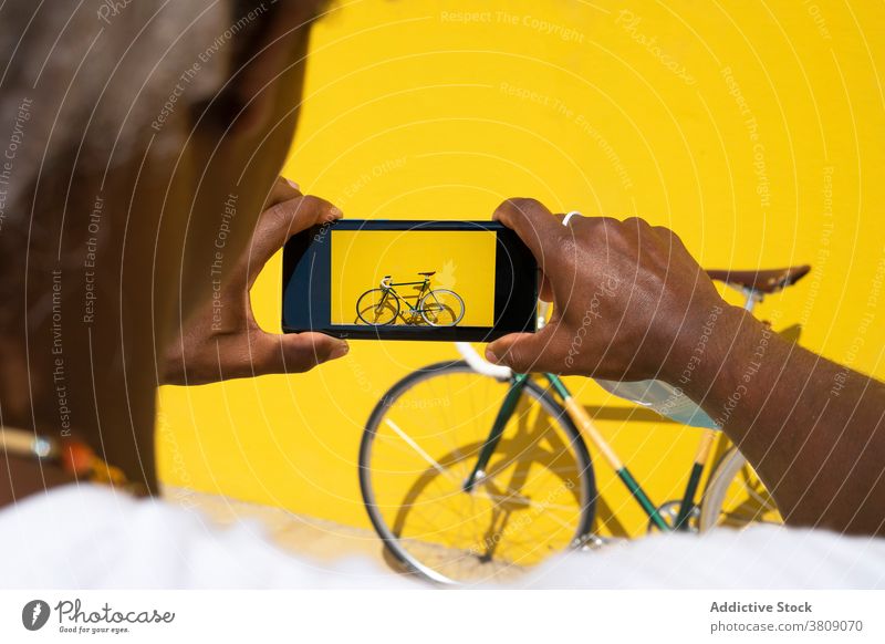 Black man taking a photo of his bike with the phone on a yellow mobile bycicle selling online sell a bycicle sell a bike selling a bike black man sell online