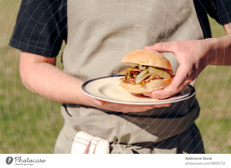 Crop man with homemade burger in village bun cook delicious countryside rustic tasty vegetable male serve apron plate appetizing fresh cuisine gourmet food