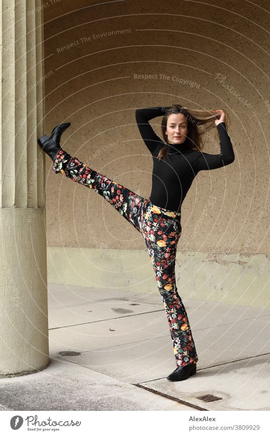 Portrait of a young dancer holding one leg up on a column Woman 18 - 30 years pretty fit Slim smart kind Pleasant Attractive Brunette Long-haired salubriously