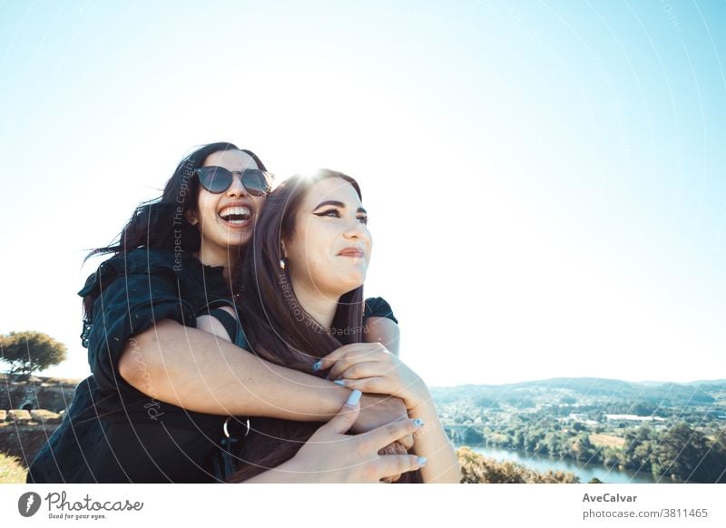 Two women having fun during a sunny day while smiling and hugging each other with copy space friendship joy female woman happiness young beautiful woman people