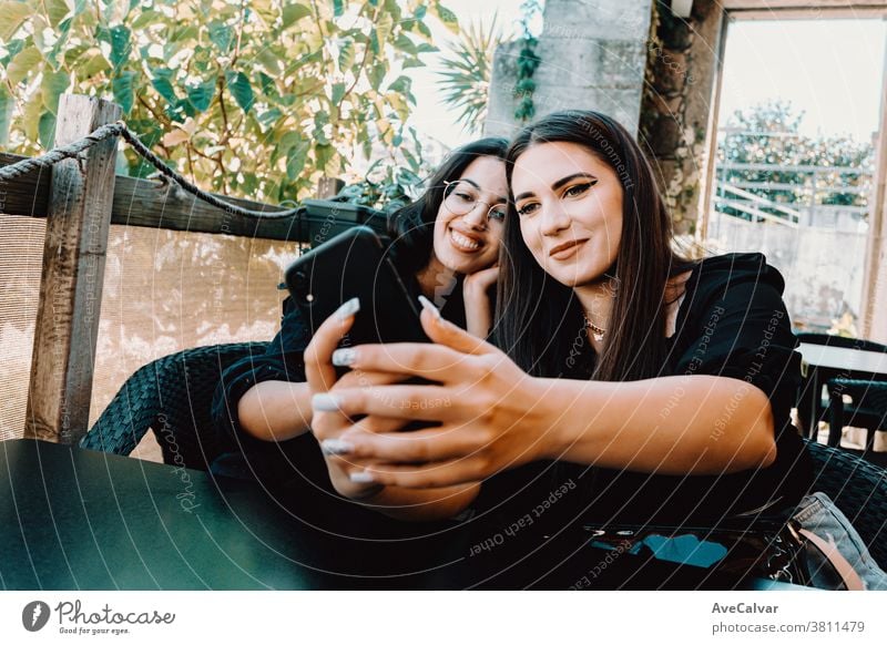 Couple of young women taking a selfie in a bar while smiling photo woman phone happy brunette friends joyful lady millennial outside smile stylish teenager two