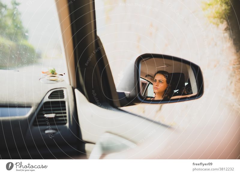 View of a young woman on the rearview mirror of a car driving transport trip road trip traffic portrait driver backview face beautiful travel attractive vehicle