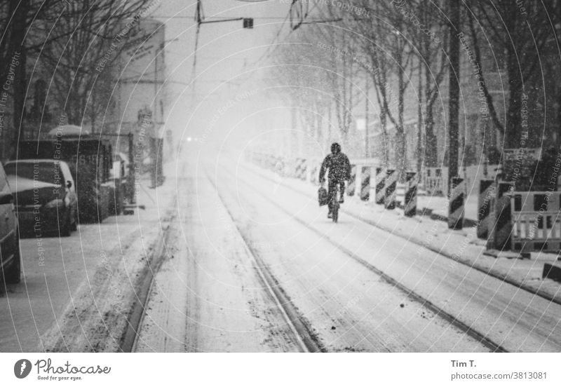 a snowy road with a cyclist in Berlin Prenzlauer Berg chestnut avenue Winter cyclists Exterior shot Downtown Town Day Old town Street Railroad tracks