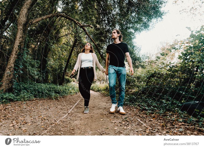 Front view of a young couple taking a walk and exploring the forest during autumn laugh fun recover cold balance wellness leisure youth time out man smile