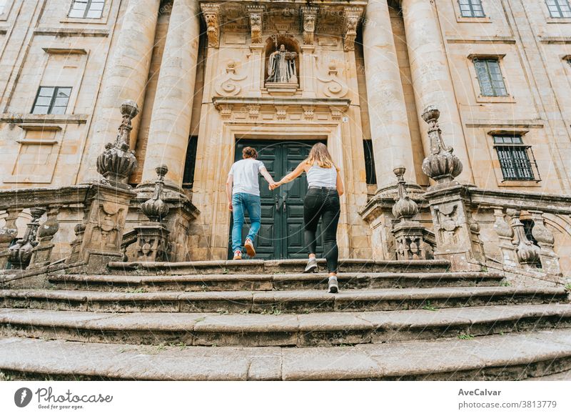Young couple going up stairs while grabbing hands in an ancient building during a sunny day outside holiday maker man staircase outdoors people male boyfriend