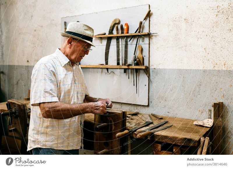 Senior male woodworker working in garage grind carpentry workshop man carpenter fold fan handmade wooden occupation skill tool messy artisan craft