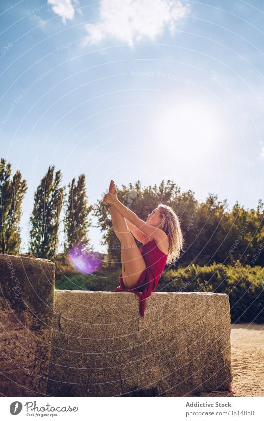 Woman in seated balancing pose practicing yoga in park woman flexible stretch balance boat urdhva mukha pascimottanasana practice position slim female wellness