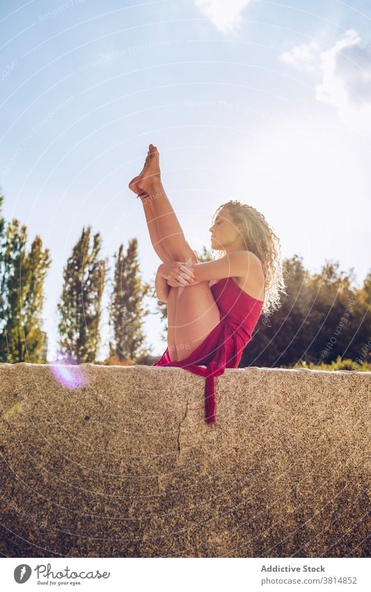 Woman in seated balancing pose practicing yoga in park woman flexible stretch balance boat urdhva mukha pascimottanasana practice position slim female wellness