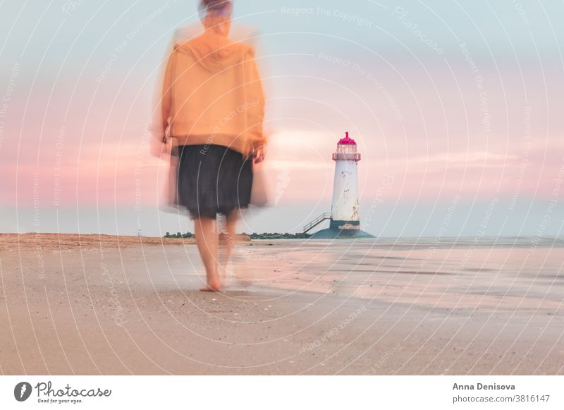 Blurry motion of moving woman towards Lighthouse blurry point of ayr talacre lighthouse shore wales sea walking person travel lady beach coast landscape britain