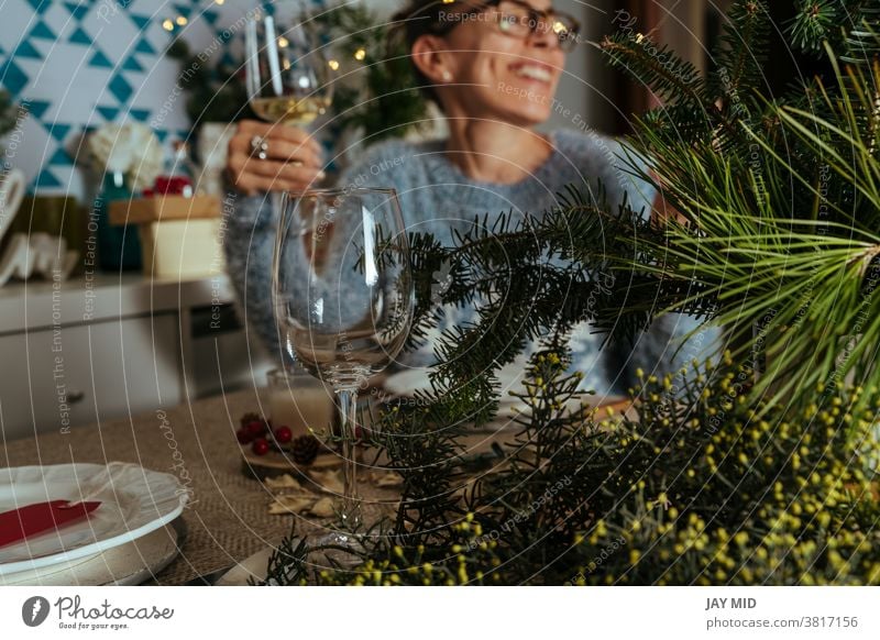 family chatting at christmas dinner, two sisters sitting at the decorated table with glasses of white wine in hand. thanksgiving women smile together talk