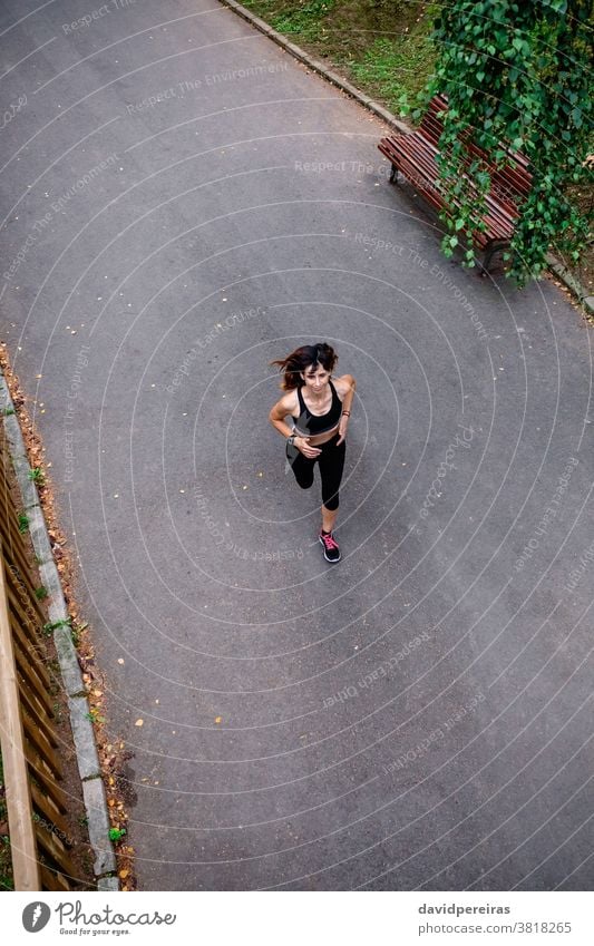 Aerial view of female runner aerial view woman running asphalt urban park enjoying overhead persevere cheerful sport top view athlete slender fitness healthy