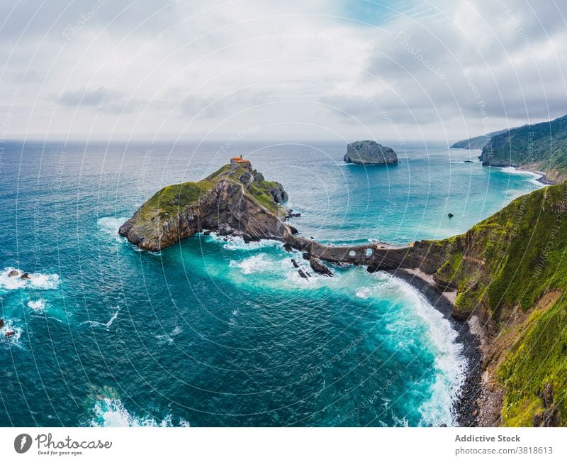 Rippled ocean near green mountain with walkway under sky gaztelugatxe nature highland san juan seascape atmosphere route landscape vegetate summer colorful