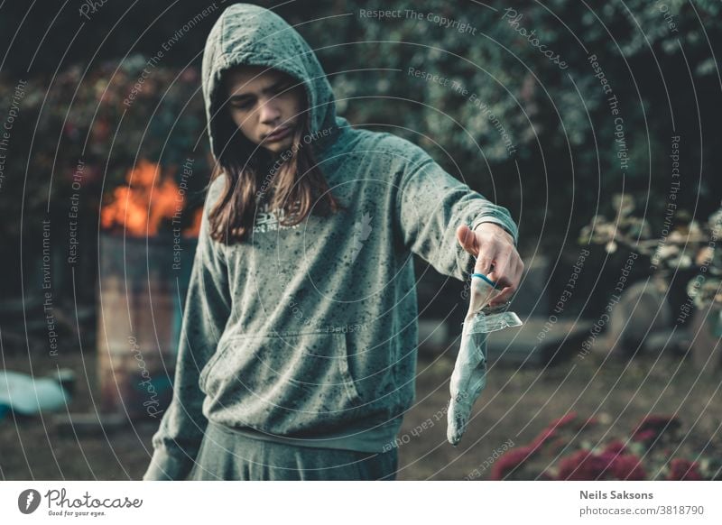 boy with long hair in green hoodie holding a glove with stuck ice plates garden gardening frozen cold Water Frost hand human human hand fingers garden glove