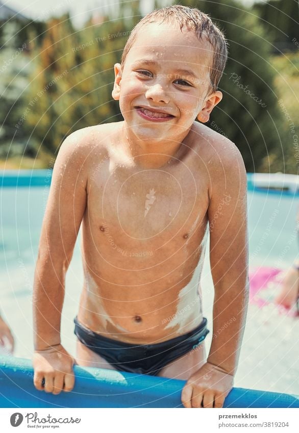 Happy boy standing in a pool authentic backyard childhood children family fun garden happiness happy joy kid laughing lifestyle playful playing real recreation