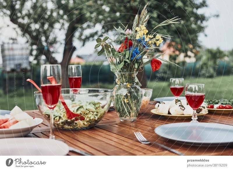 Dinner in an apple orchard on wooden table with salads and wine decorated with flowers home feast picnic food summer barbecue dinner gathering lifestyle meal