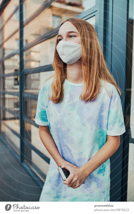 Portrait of young woman girl standing at store front downtown wearing face mask to avoid virus infection caucasian cellphone conversation covid-19 female