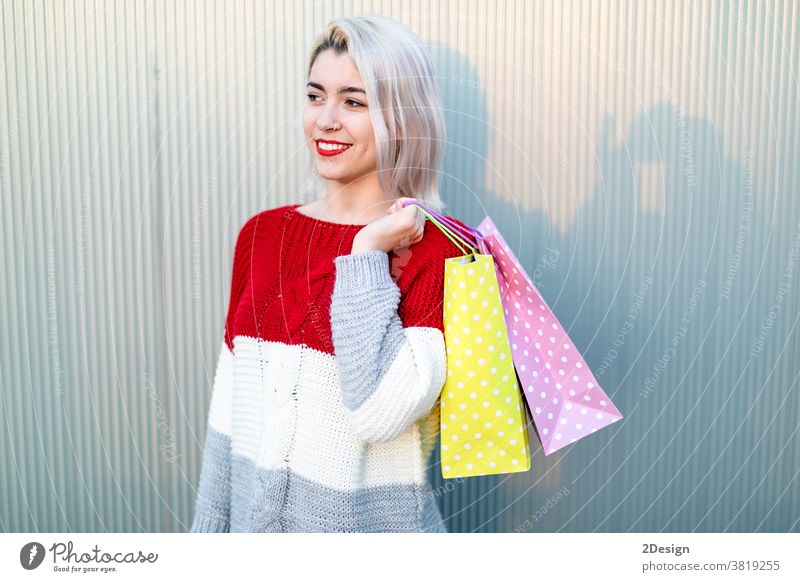 Portrait of young happy smiling woman with shopping bags standing 1 shopper happiness beautiful female purchase girl shopaholic person outdoor lady pretty