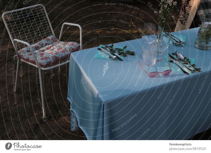 set garden table with blue tablecloth, garden chair, flower cushion and sunglasses Garden Life Outdoor furniture Summerfest laid table in common tepid
