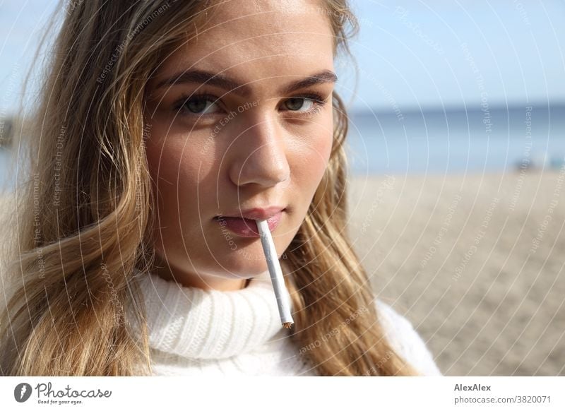 Blonde girl is standing on the east beach and has a self-rolled cigarette in her mouth Landscape Beach Intensive teen kind Nature feminine Uniqueness