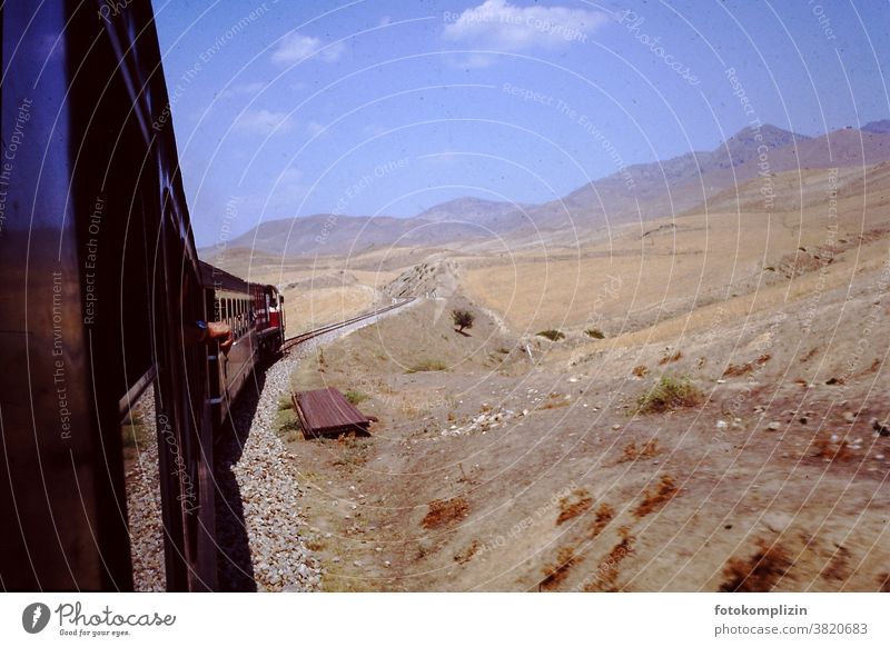 View from a moving train into a dry mountainous landscape Train train ride Old Retro Desert Landscape Dry Steppe Hot South Far-off places wide Train travel