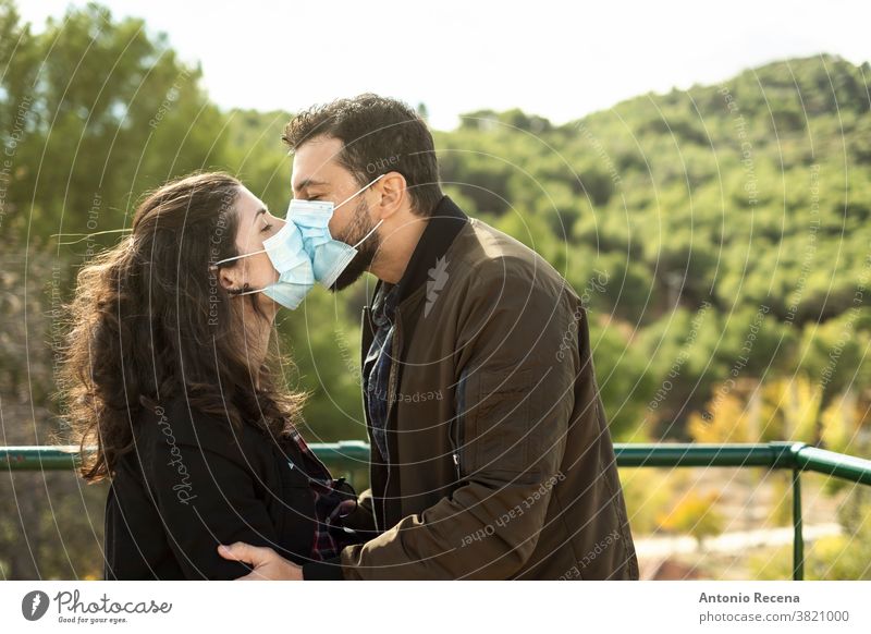 Couple kisses outdoors with a surgical mask. Outdoor portrait symbolizing pandemic love couple valentines covid-19 coronavirus woman nature people lifestyle 30s
