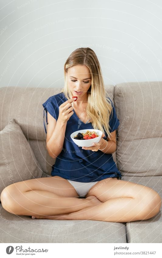 Young woman eating an vegan appetizer with nuts, raspberries and blackberries. healthy food diet vegetarian girl meal fresh nutrition lifestyle breakfast bowl