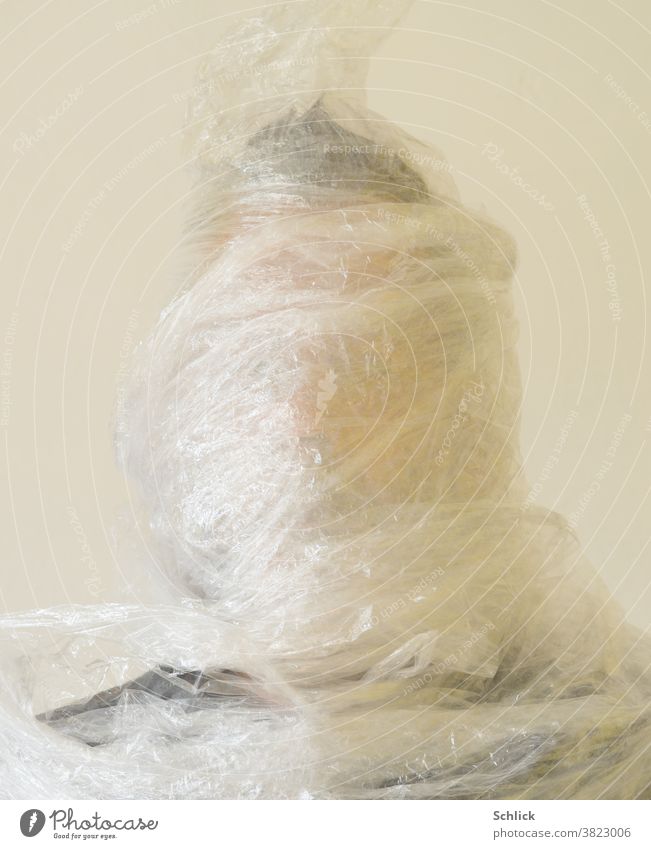 Plastic mania Head of a man wrapped in stretch foil Packing film plastic portrait Wrapped around Man stretch film Environmental protection plastic waste Trash