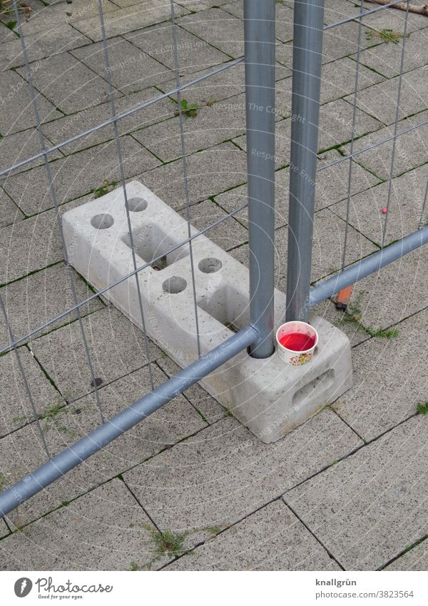 Paper cup with red drink in the holder of a construction fence Beverage Hoarding Mug cup holder Food Deserted Concrete Bracket Metal Metalware Fence Barrier