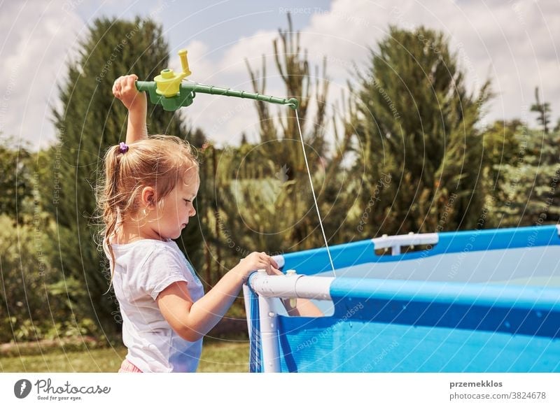 Children playing with fishing rod toy in a pool in a home garden authentic backyard childhood children family fun happiness happy joy kid laughing lifestyle