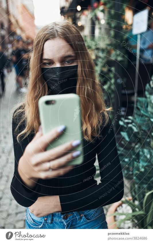 Young woman having video call talking while walking downtown wearing the face mask to avoid virus infection care caucasian chat contagious corona coronavirus