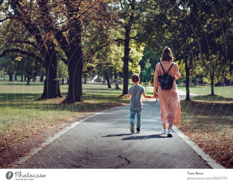 Hand in hand mother with child walking through an autumnal park Town To go for a walk Promenade stroll take a walk Hold hands Child Mother with son Young woman