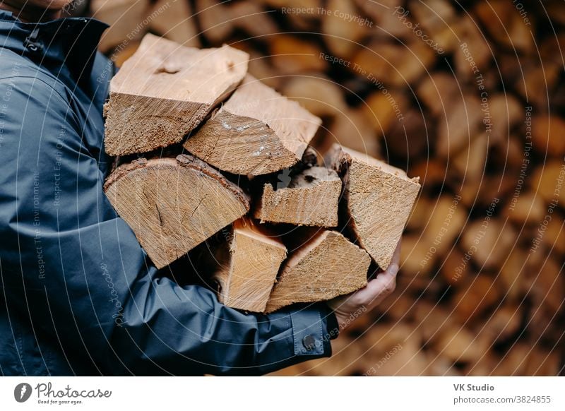 Unrecognizable man carries heap of wood for making fire dressed in jacket. Faceless male carries firewood into house wooden outdoors log fuel chop woodcutter