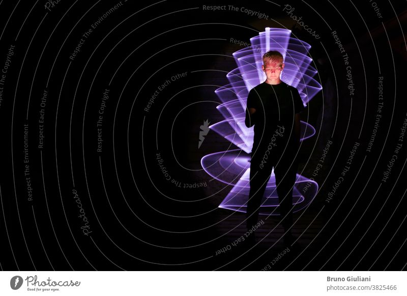 Silhouette of a man using a smartphone. Abstract form in light painting with a lightsaber. Face illuminated by the screen. Light painting Man futuristic