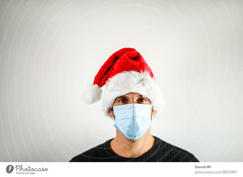 Corona and Christmas - Man with breathing mask and Santa cap Mask corona Santa Claus hat advent season pandemic coronavirus Risk of infection Protection Healthy